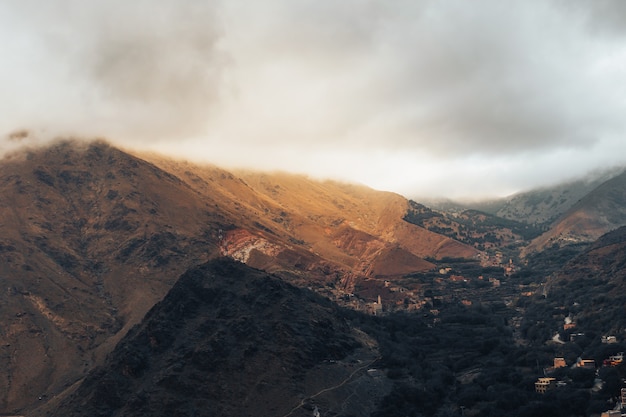 Le magnifique paysage naturel nuageux avec les montagnes de l'atlas marocain avec petit village ci-dessous