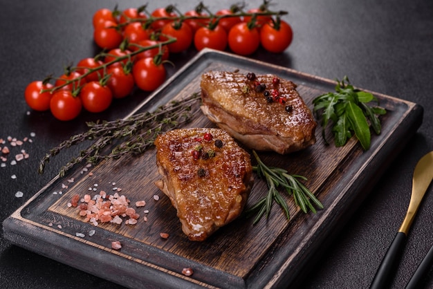 Magret de canard au four aux herbes et épices sur une table sombre. Viande frite prête à manger