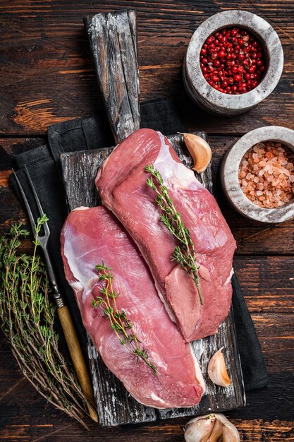 Magrets de canard crus, steaks de viande de volaille sur planche de bois prêts pour la cuisson. Fond en bois. Vue de dessus.