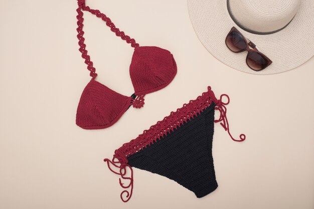 Maillot de bain bordeaux, chapeau et lunettes de soleil. Armoire de plage. Concept à la mode