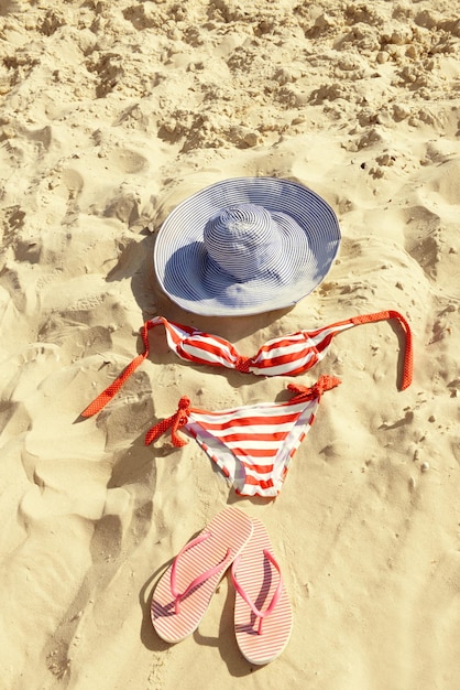 Maillot de bain tongs et chapeau sur le sable de la plage libre