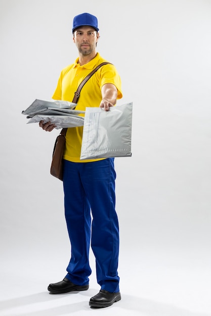 Mailman brésilien sur fond blanc la livraison d'un colis. copie espace.