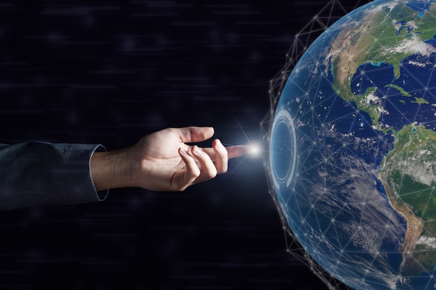 Main d'affaires touchant le réseau mondial et les échanges de données à travers le monde dans l'obscurité. Éléments de cette image fournie par la NASA