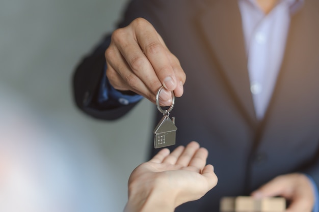 main de l&#39;agent immobilier / propriétaire donnant la maison clé à l&#39;acheteur / locataire.