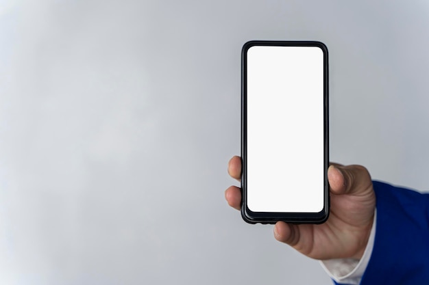 Main à l'aide d'un écran de smartphone blanc sur fond de surface grise vue de dessus en gros plan
