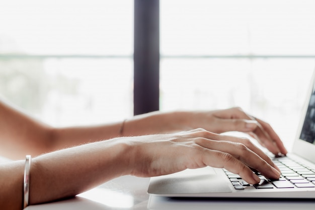 Main à l'aide d'un ordinateur à la maison pour travailler, e-learning et réseau social