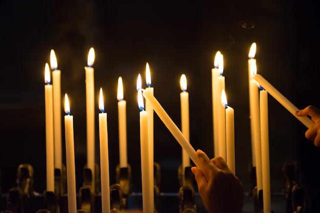 Main allume des bougies dans l'église sur le fond noir