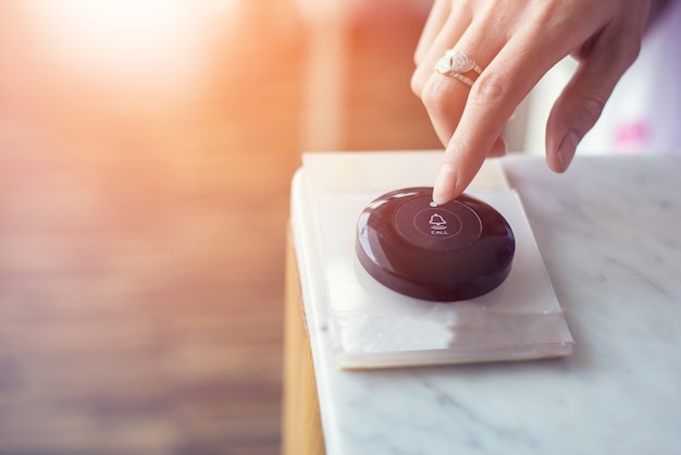 Main en appuyant sur le bouton d&#39;appel sur la table