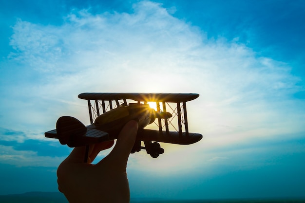 La main avec un avion jouet sur fond de lever de soleil