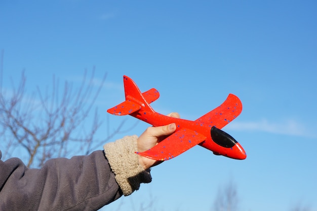 Main avec avion jouet sur la surface du ciel, concept de voyage aérien