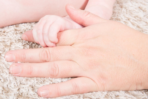 Main bébé qui dort dans les mains mère gros plan