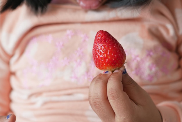 Main de bébé tenant une fraise