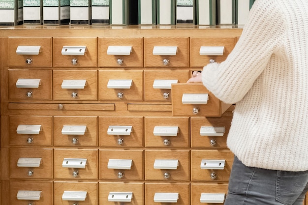 Une main de bibliothécaire ouvre une carte de bibliothèque ou une boîte de catalogue de fichiers