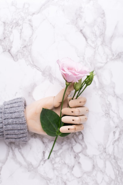 Main en bois avec fleur sur marbre