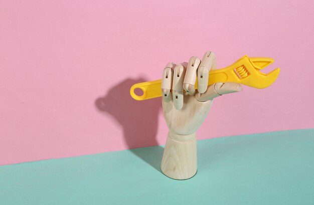 Photo main en bois tenant une clé à jouet sur fond pastel rose bleu ombre à la mode concept art minimalisme mise en page créative