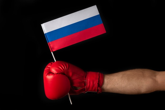 La main des boxeurs tient le drapeau de la Russie. Gant de boxe avec le drapeau russe. Isolé sur fond noir.