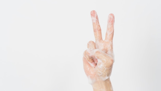 Main avec bulle de savon en mousse fait signe de la main de la victoire ou de la paix