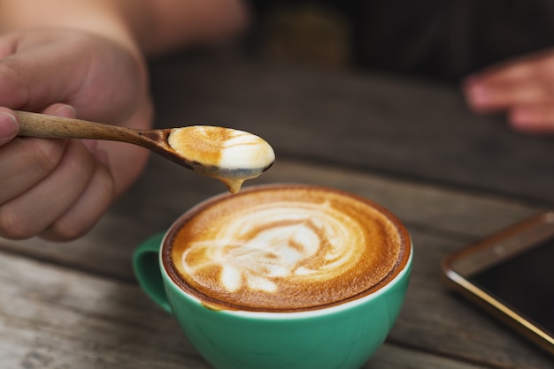 Main cappuccino café dans une tasse verte en bois