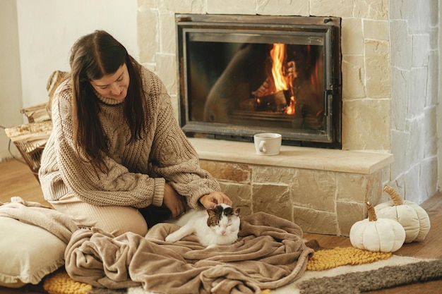 Main caressant un chat mignon sur une couverture douillette à la cheminée close up hygge d'automne