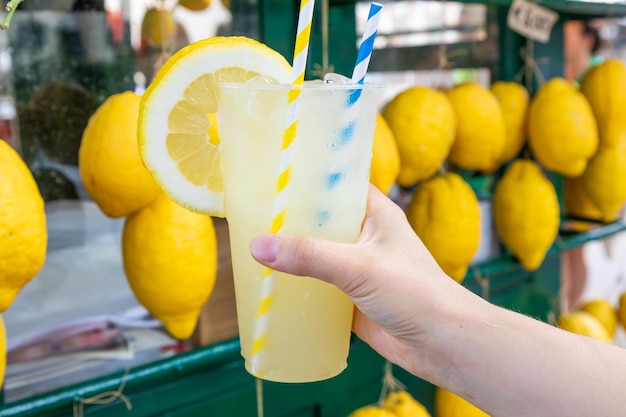 Main caucasienne avec de la limonade fraîche et saine pendant l'été fond de citrons