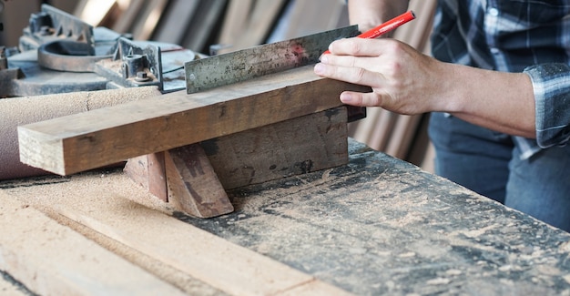 Main de charpentier travaillant sur le travail du bois à mesurer le bois avec une règle et un crayon