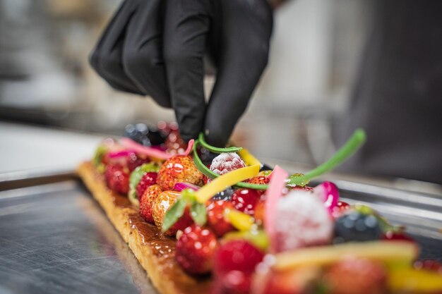 Main d'un chef plaçant des ingrédients dans une tarte aux fruits