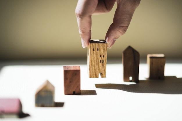 Main choisissant mini modèle de maison en bois à partir du modèle, mise au point sélective,