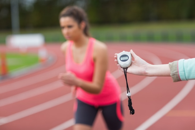 La main chronométrant la course d&#39;une femme sur la piste de course