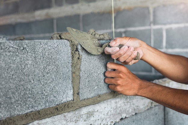 Main de ciment de plâtrage de travailleur au mur pour la construction de maison