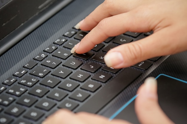 main sur le clavier noir d'un ordinateur en tapant du texte