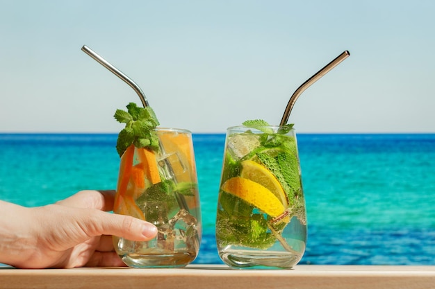 Main avec cocktail gin tonic sur la plage d'été