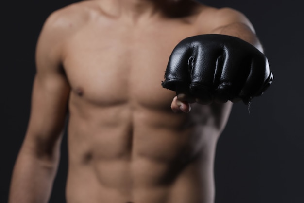 Main de combattant masculin de plan rapproché avec le gant de MMA. Le combattant a serré le poing avant un combat ou un entraînement dans une salle de sport.