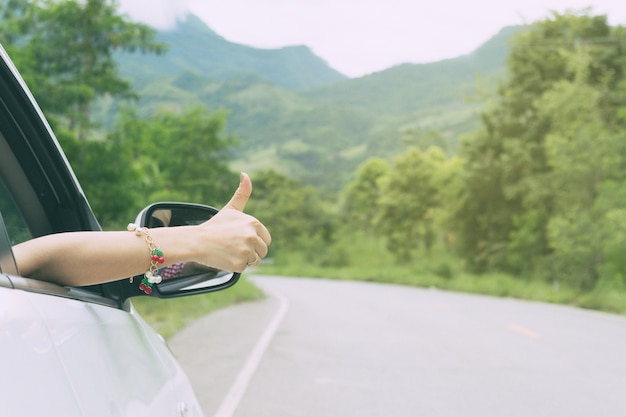 Main comme la voiture de pouce sur la route avec voyage