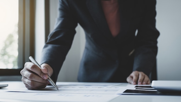 Main de comptable de femme d'affaires tenant un stylo et utiliser un ordinateur portable faisant compte pour payer l'impôt sur un bureau blanc au bureau de travail.