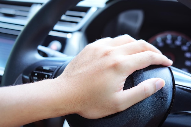 Photo main de conducteur de voiture appuyant sur le klaxon dans les volants en gros plan