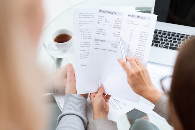 Photo main de conseiller financier avec stylo pointant sur somme dans le document tout en expliquant les détails au client va ouvrir un compte bancaire