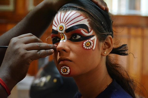 Main coupée appliquant du maquillage sur une femme pendant le carnaval