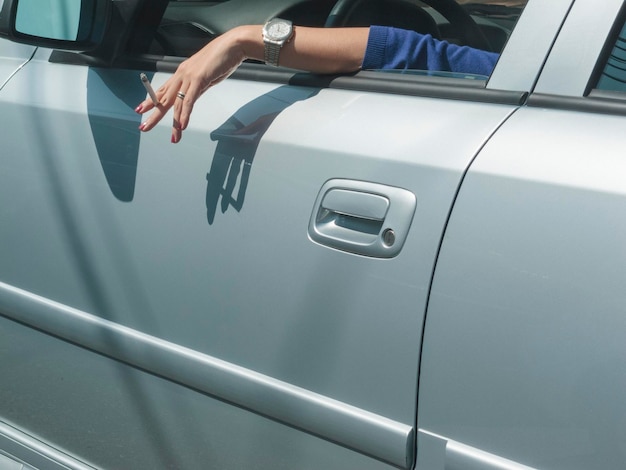 Photo main coupée avec une cigarette dans la voiture