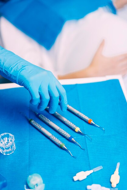 Photo main coupée d'un dentiste ramassant de l'équipement dentaire sur la table