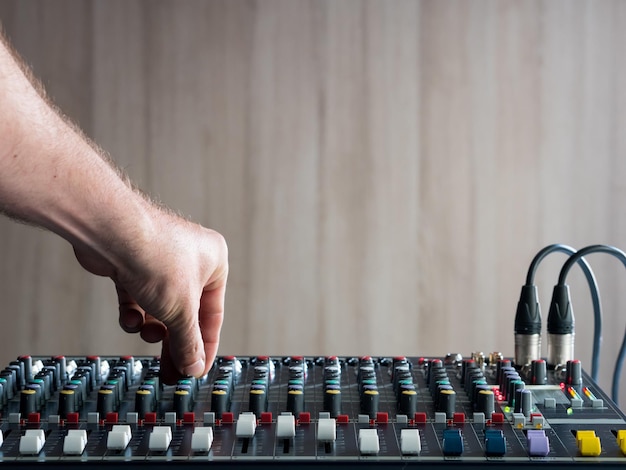 Photo main coupée d'un dj masculin jouant de la musique sur un mixeur de son contre le mur