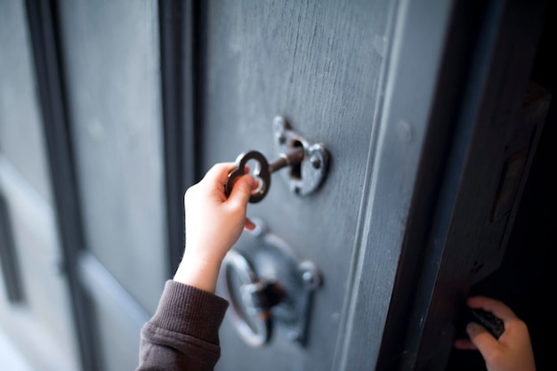 Main coupée d'un enfant déverrouillant la porte à la maison