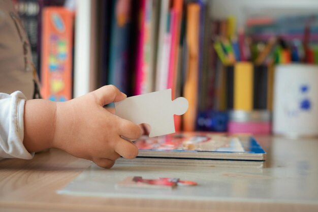 Photo la main coupée d'un enfant tenant un puzzle sur la table