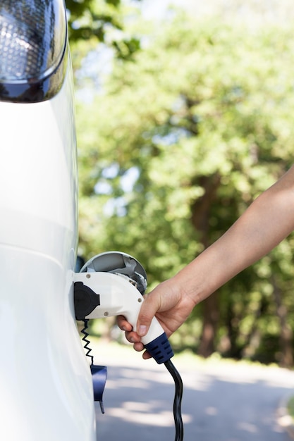Main coupée d'une femme chargant une voiture électrique à la gare