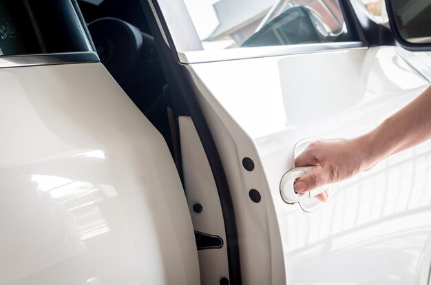 Photo main coupée d'une femme ouvrant la porte de la voiture