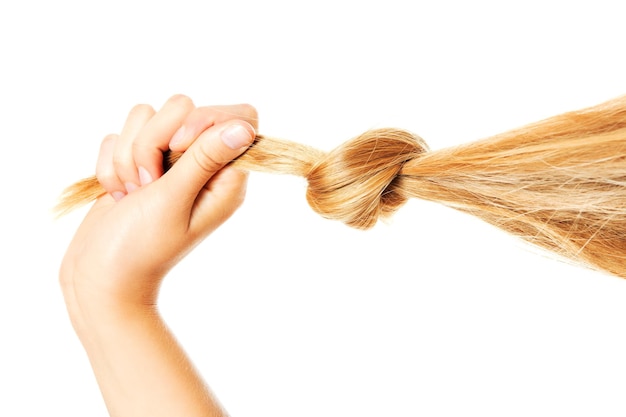 Main coupée d'une femme tenant des cheveux sur un fond blanc