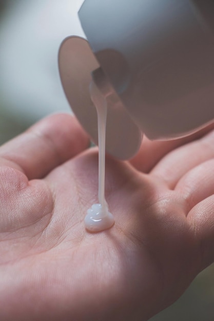 Main coupée d'une femme tenant une lotion pour le corps