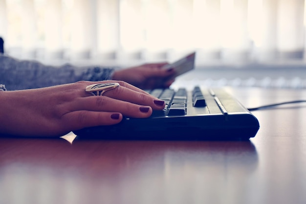 Main coupée d'une femme utilisant un ordinateur sur la table