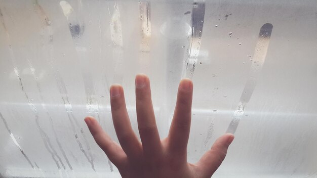 Main coupée sur une fenêtre condensée dans la salle de bain