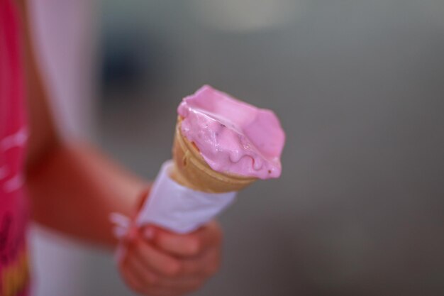 Photo la main coupée d'une fille tenant un cône de crème glacée