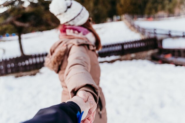 Photo main coupée d'un homme tenant une femme sur une terre couverte de neige